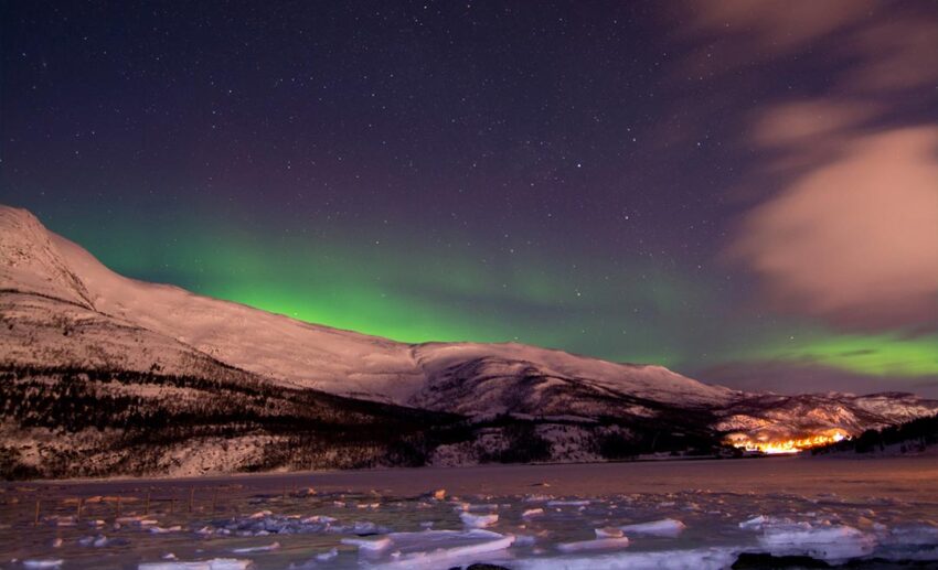A natural display of the green Aurora Borealis, or northern lights, dancing across a dark high-latitude sky.