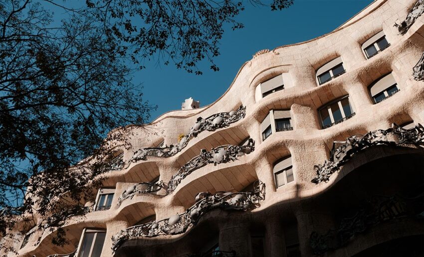 The exterior of La Pedrera (Casa Milà) by Antoni Gaudí in Barcelona, showing unique balconies and stone architecture designed for natural temperature regulation.