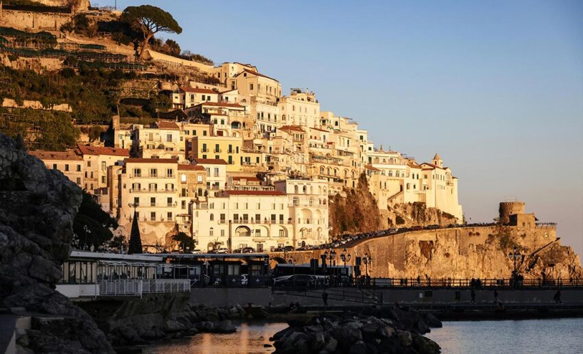 A stunning sunset landscape of Amalfi’s hillside houses and coastal architecture overlooking the Mediterranean Sea in Italy.