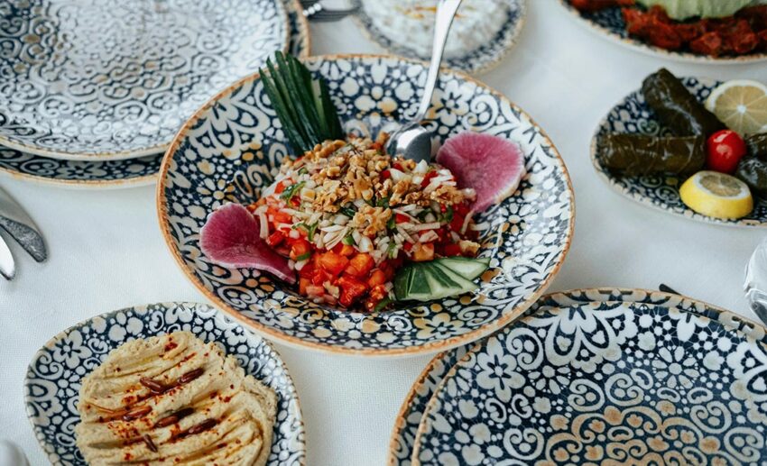A table filled with a variety of Mediterranean diet dishes, including fresh salads, seafood, and appetisers in a coastal outdoor setting.
