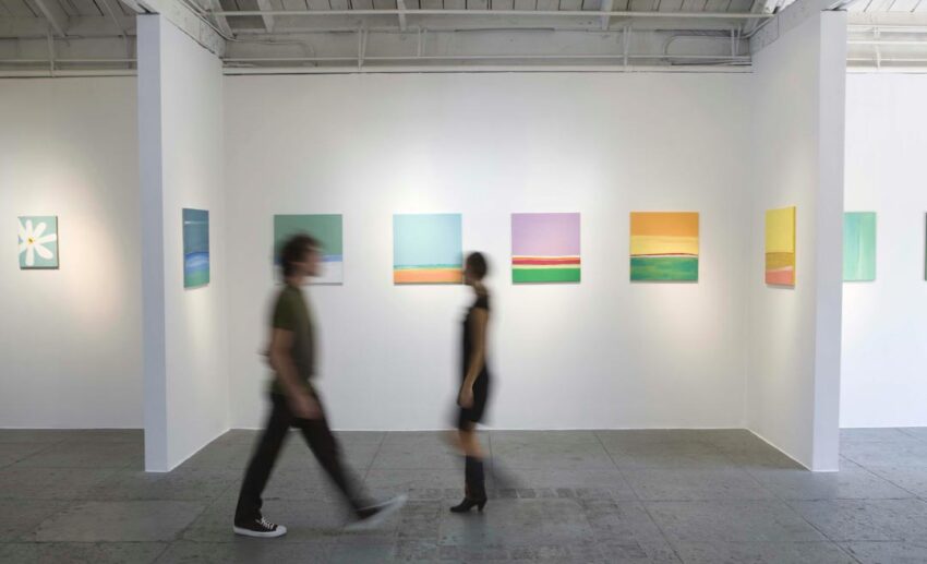 People walking through a museum exhibition room while viewing art and cultural displays.