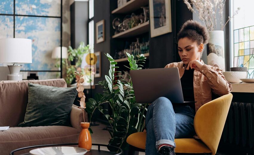 A focused woman working on a laptop in a stylish, modern home office, representing a professional travel advisor managing complex bookings.