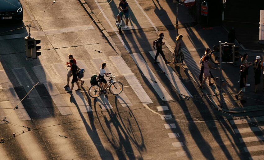 Pedestrians and cyclists crossing a city street during a quiet, cool morning commute.