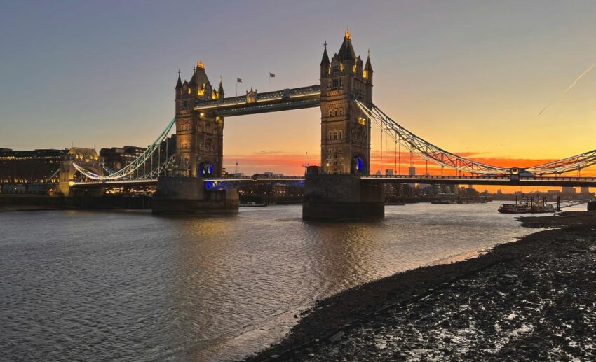 A vibrant sunrise over Tower Bridge in London with empty roads and a clear sky.