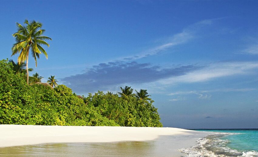 A quiet, empty tropical beach in the Maldives with white sand and turquoise water, illustrating the low elevation of the island nation.