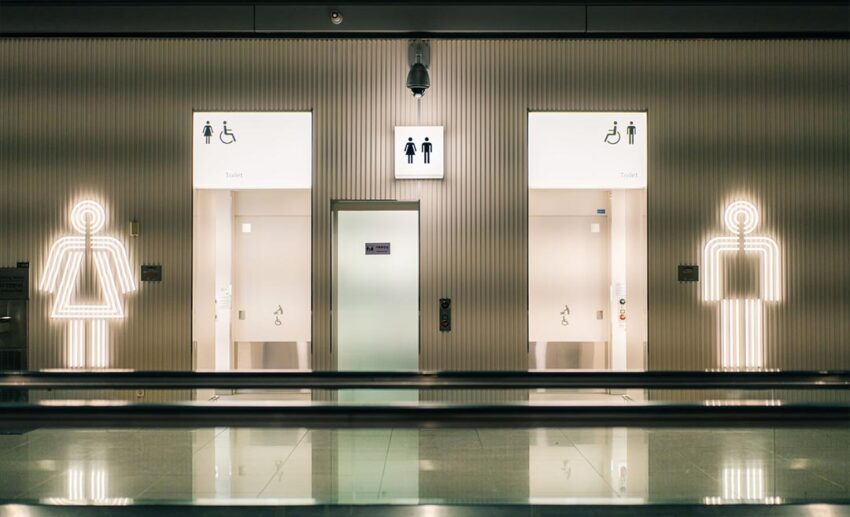 Modern public restroom signs with a wheelchair accessibility symbol inside a clean airport terminal.