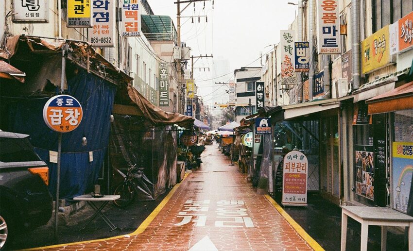 A street in Seoul featuring a bright orange lane painted on the road with white Korean instructional text.