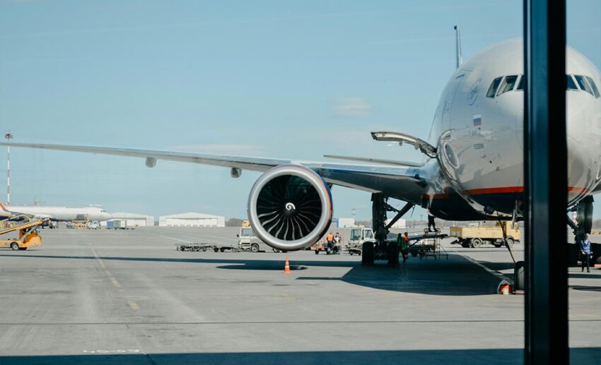 A commercial airliner parked on an airport runway during the day, representing travel logistics and coordination.