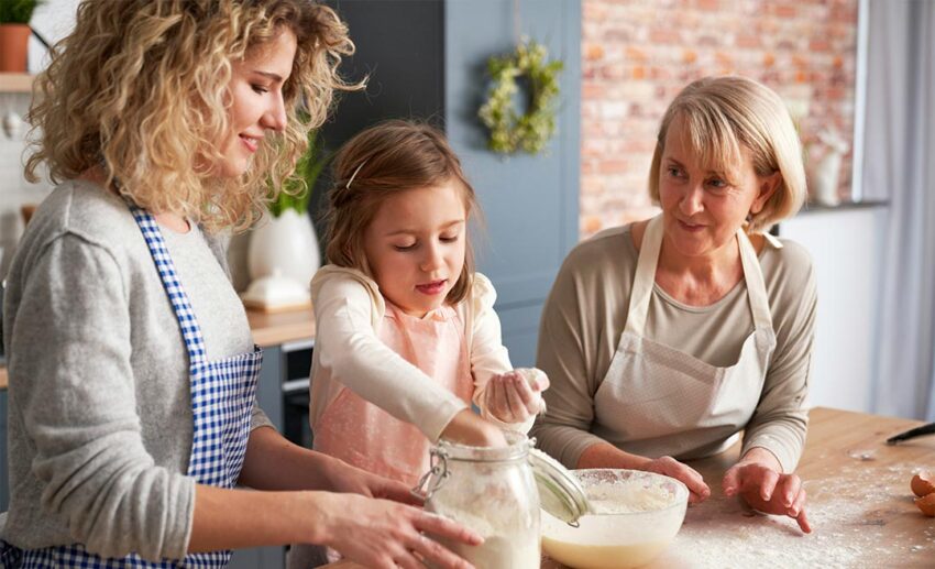 A young girl, her mother, and her grandmother baking together in a kitchen during a traditional Easter holiday.