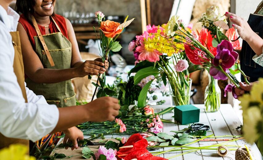 A group of women participating in a hands-on floral design and flower-arranging workshop.