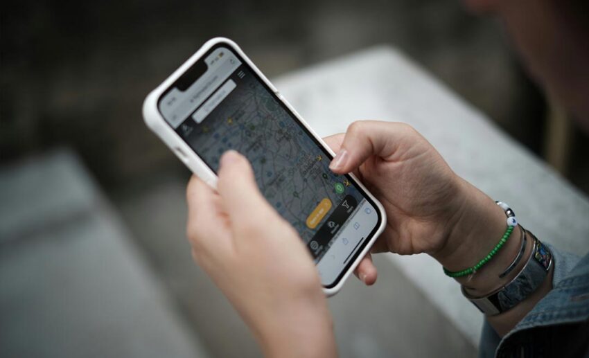 A person holding a smartphone showing a digital map app, used for researching alternative flight routes around affected airspace.