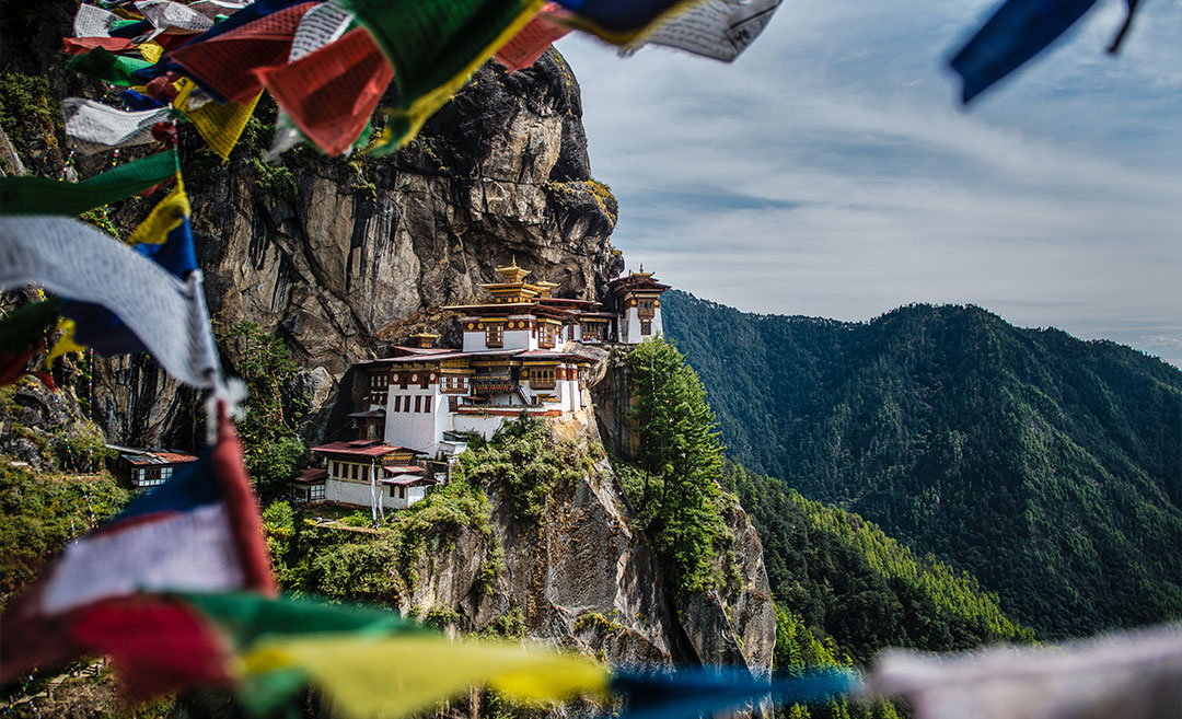 The Tiger’s Nest Monastery (Paro Taktsang) perched on a cliff in Bhutan under a clear sky, representing a bucket-list destination requiring careful seasonal planning.