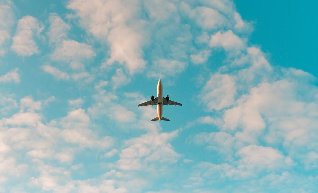 Low-angle daytime view of an aeroplane flying through a clear sky, showing the underbelly of the aircraft.