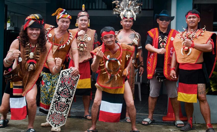 A group of Dayak men in full traditional warrior attire and accessories posing together during Gawai celebrations in Serian, Sarawak.
