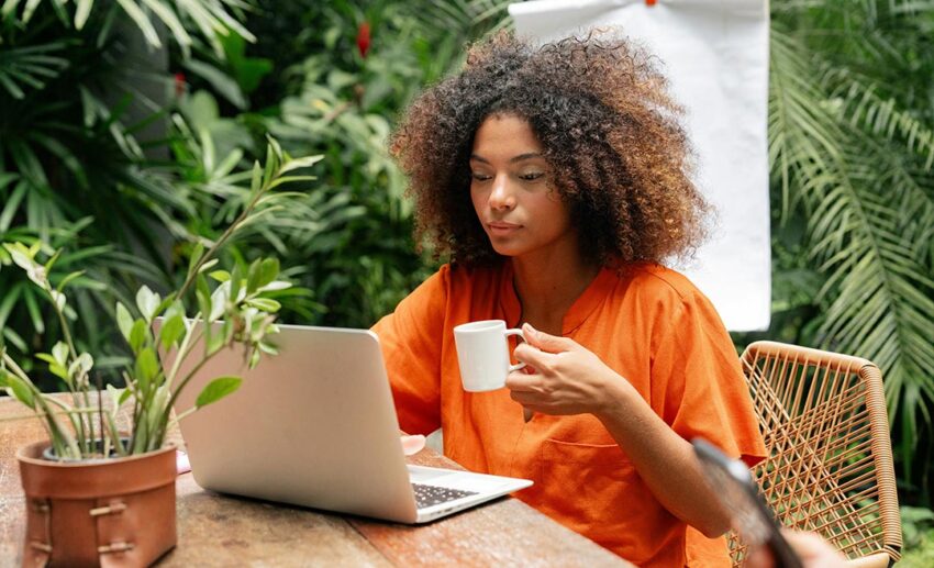 A focused woman managing financial planning on a laptop computer at a table while preparing for a mid-career sabbatical.