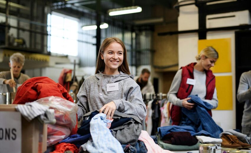A group of women volunteering together by sorting through donated clothes at a community charity center while travelling abroad.