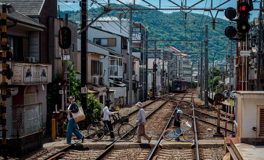 Local residents and travellers crossing pedestrian train tracks in a quiet, traditional Japanese town during a slow travel trip.