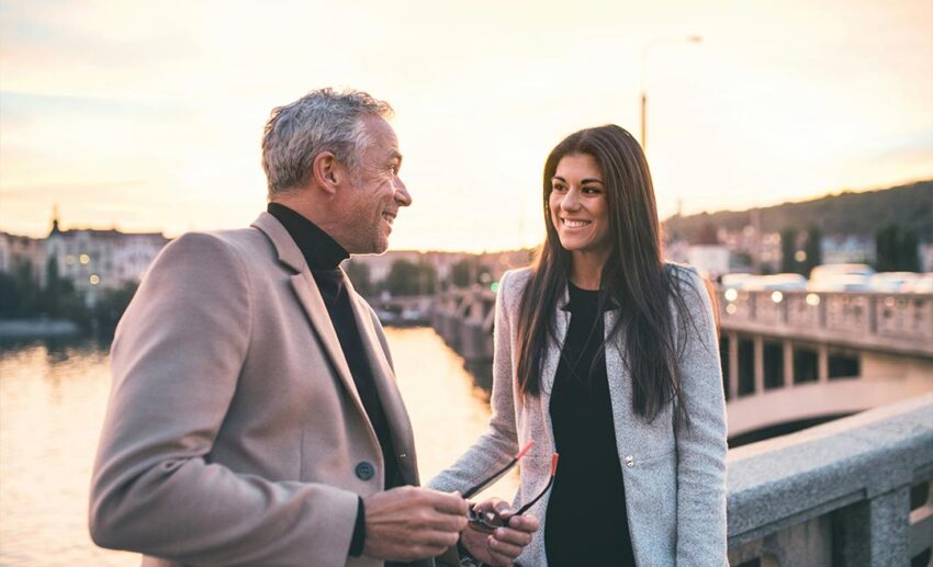 Father and daughter standing by the Vltava River in Prague at dusk discussing their European vacation landmarks