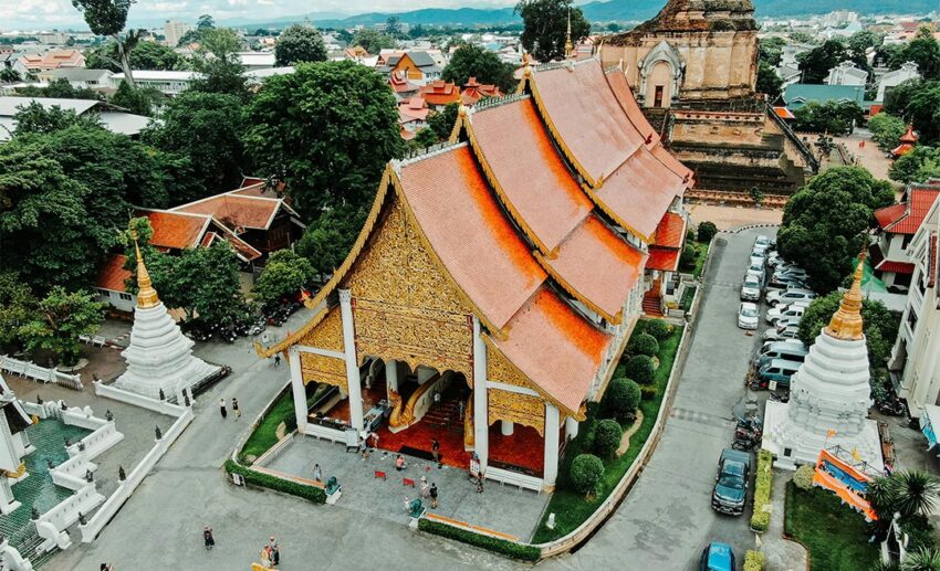 The intricate architecture and golden details of a traditional Buddhist temple under a blue sky in Chiang Mai, Thailand.