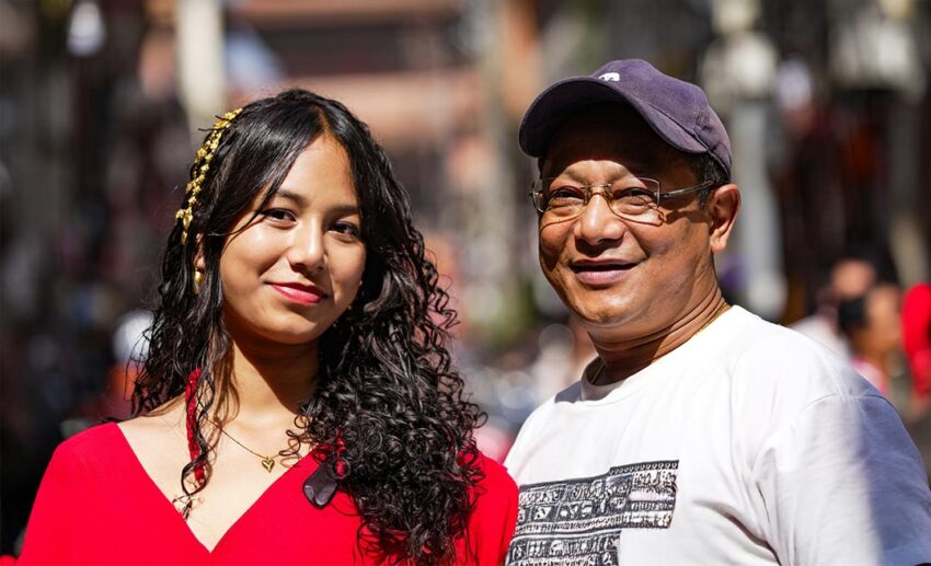 Young woman smiling next to her older father on neutral ground during a meaningful family vacation