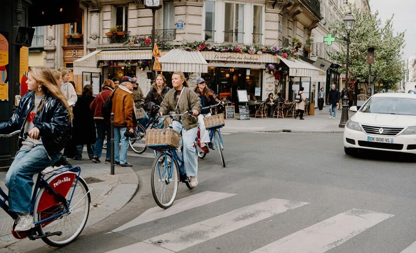 Local residents and commuters cycling down a beautiful city street past classic Parisian architecture in Paris, France.