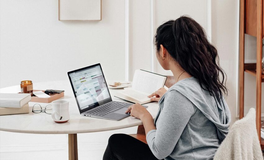 A focused woman using a slim laptop at home to safely research immigration requirements and learn how to live abroad through official sites.