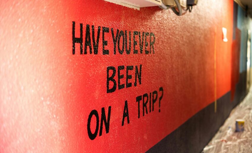 A red wall featuring a white conceptual text sign that reads "Have you ever been on a trip?".