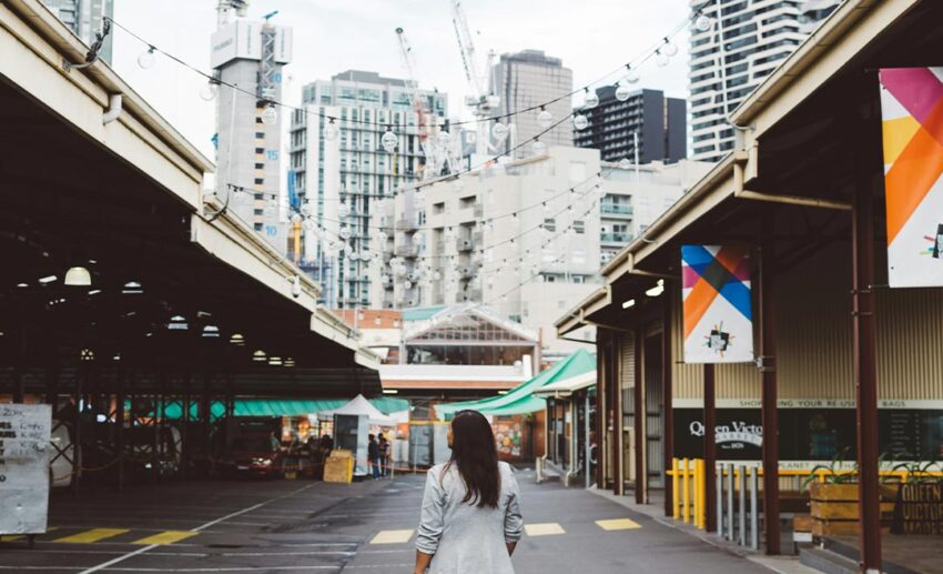 A woman standing confidently on a street between residential buildings in a foreign city during a relocation trial.