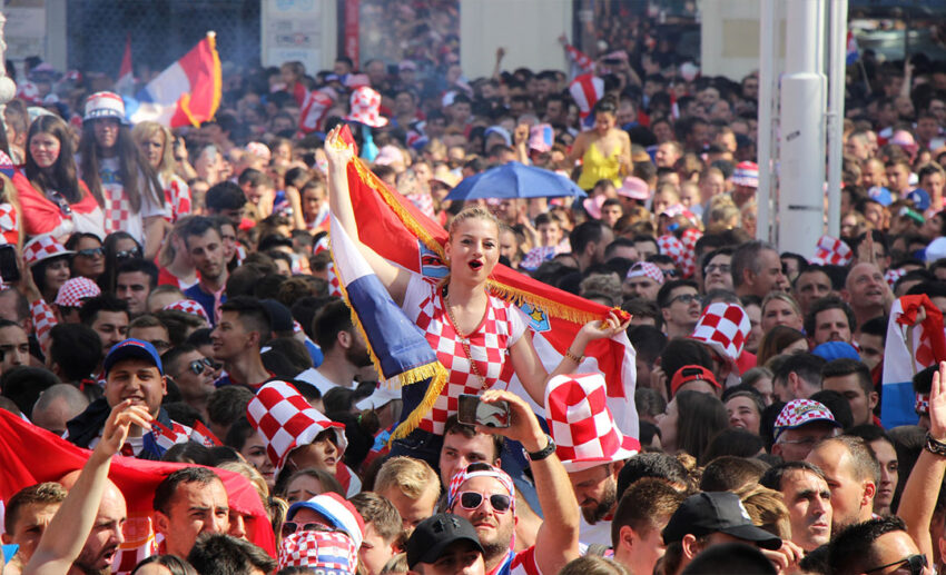 A massive crowd of passionate Croatian football fans gathered closely together at Ban Jelacic Square in Zagreb to watch a FIFA World Cup match, illustrating the powerful cultural exchange and global community spirit of the tournament.