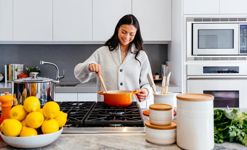 A woman preparing a meal thoughtfully in a sunlit kitchen during an extended stay