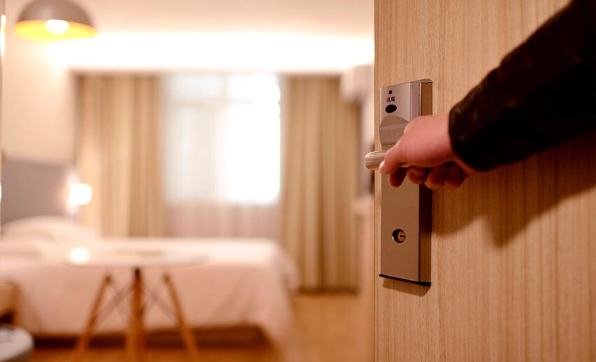 A close-up of a person opening a hotel room door