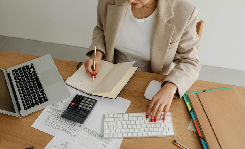 A woman sitting thoughtfully at her desk working on a desktop computer, balancing family expectations and career.