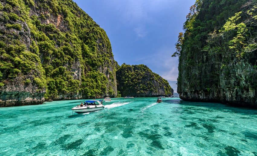 The clear turquoise lagoon of Pileh Bay surrounded by towering limestone cliffs on Phi Phi Island in Krabi, Thailand, representing popular tropical holiday destinations.