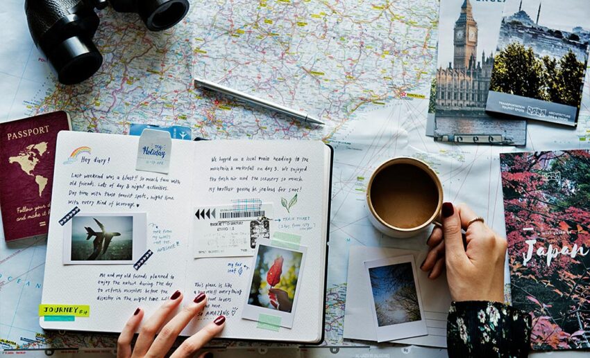 A flat lay view of travel planning essentials with a map, passport, and camera, showcasing lifestyle design for Asian women.