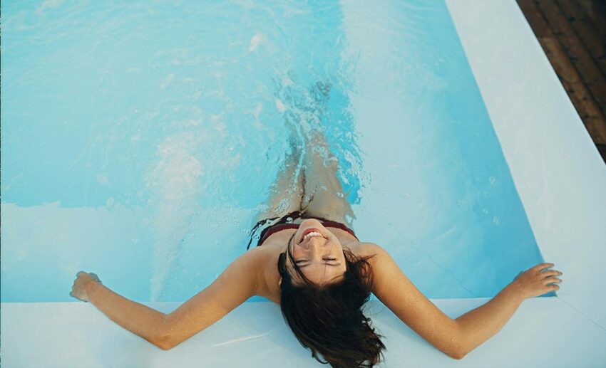 High-angle view of a brunette woman relaxing in a luxury resort swimming pool hot tub during a summer holiday vacation.