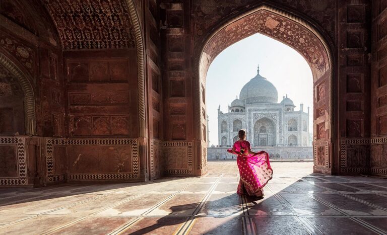 Solo female traveller in a pink sari looking at the Taj Mahal in Agra, India, highlighting independent women's travel preparation.