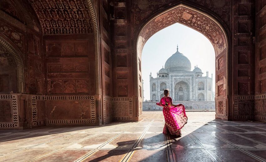 Solo female traveller in a pink sari looking at the Taj Mahal in Agra, India, highlighting independent women's travel preparation.
