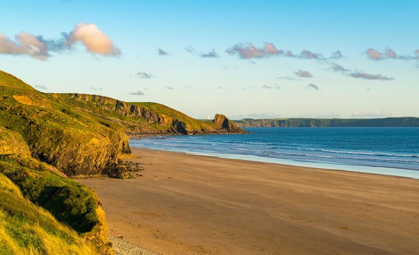 Wide expanse of quiet, empty sand and pebbles at Newgale Beach during a tranquil evening