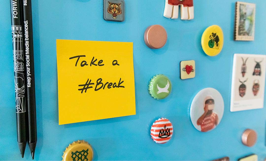 A blue refrigerator door decorated with magnets and a yellow sticky note reading Take a Break