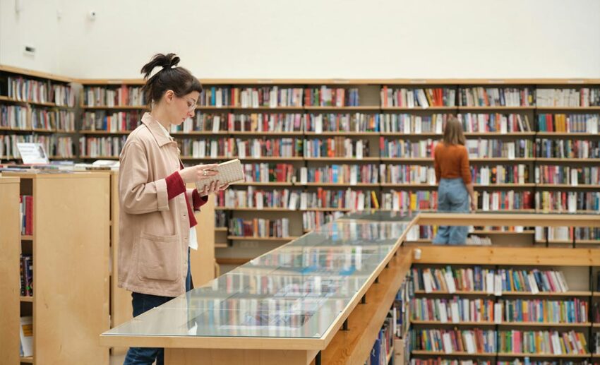 Group of young people standing individually, browsing shelves, and choosing books inside a bookstore