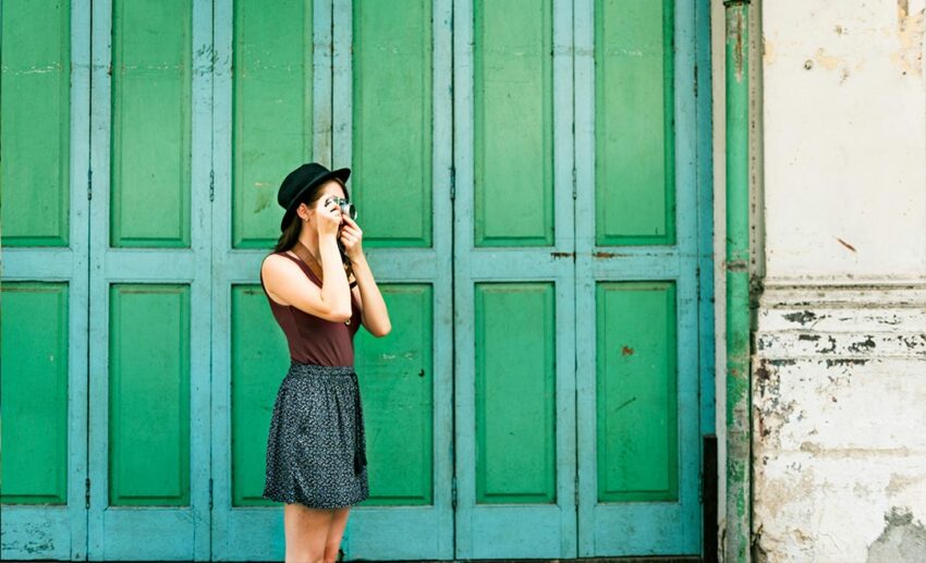 Woman with a camera taking photos while exploring a street during her holiday travels