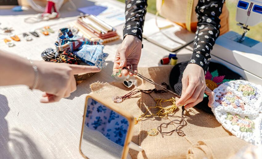 Close-up of a traveller pointing to handmade artisan jewellery at an outdoor market stall