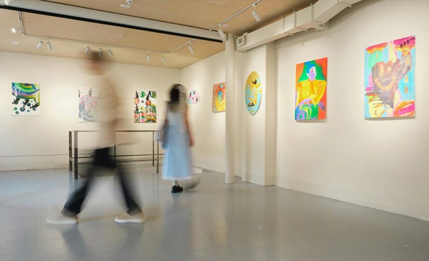 Visitors browsing a brightly lit contemporary art gallery space featuring large, colourful artwork during an indoor cultural activity in Malaysia