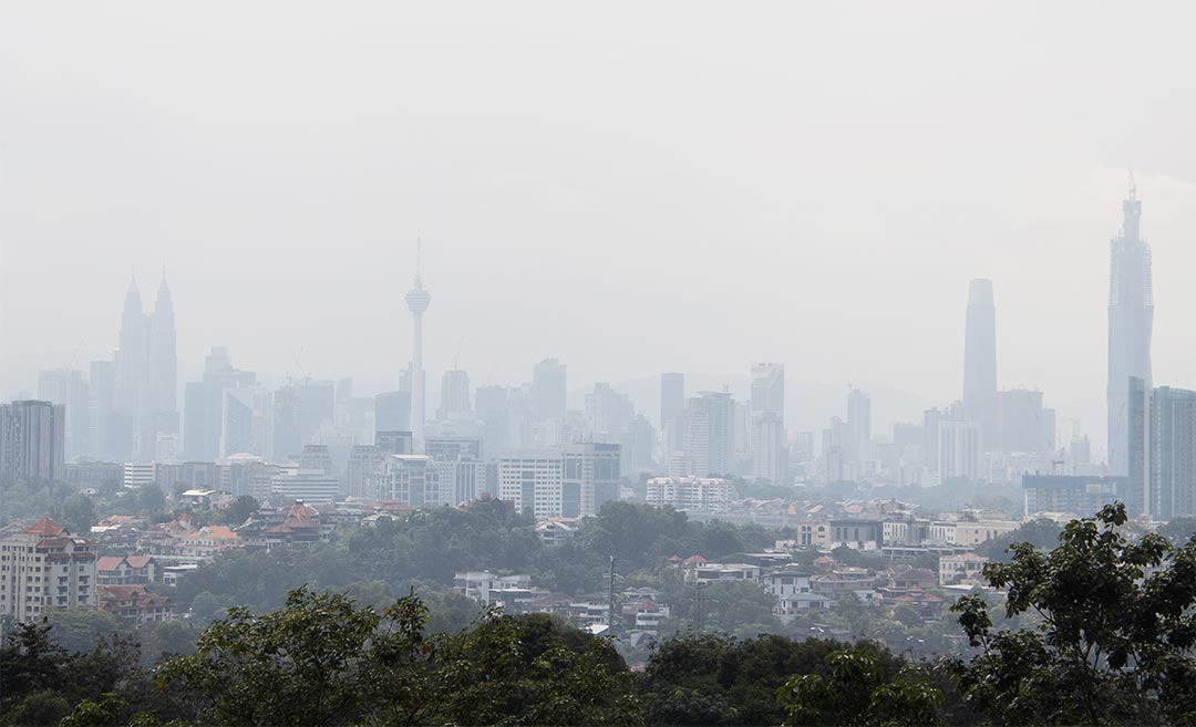 Panoramic skyscape of the Kuala Lumpur skyline obscured by thick, grey transboundary haze caused by regional forest fires in Southeast Asia.