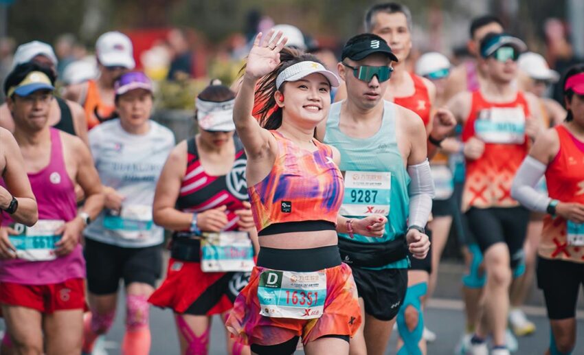 Smiling female runner waving during the 2025 Taiyuan marathon race.