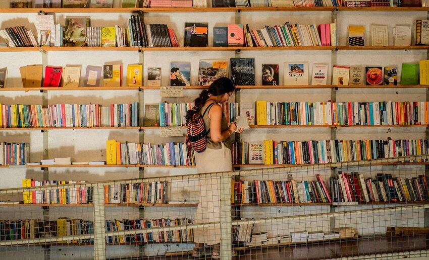 Woman browsing books on wooden shelves inside a traditional bookstore in Lisbon, Portugal.