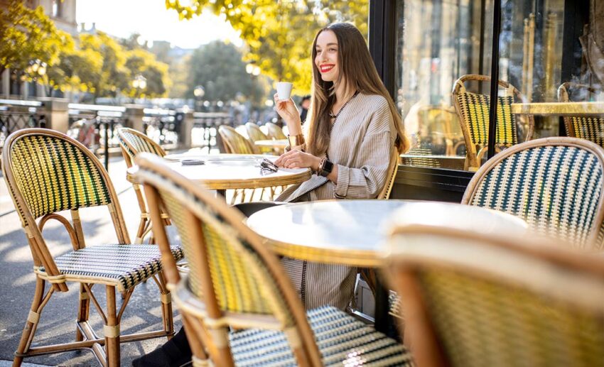 Woman sitting at a small outdoor table enjoying morning coffee at a traditional French bistro in Paris