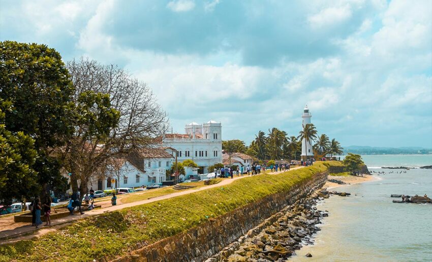 Distant shot of people walking along the coastal sidewalk at Galle Fort in Galle, Sri Lanka