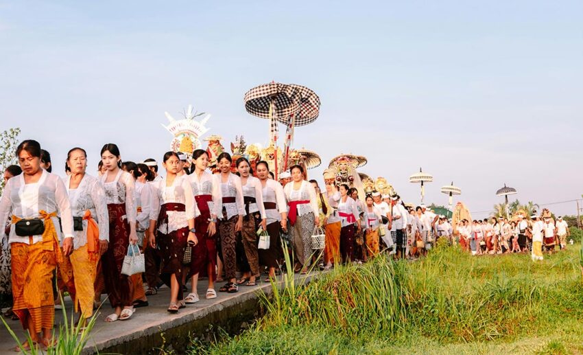 Balinese villagers wearing traditional white ceremonial attire walking in the Melasti procession in Desa Adat Abiansemal, Bali.