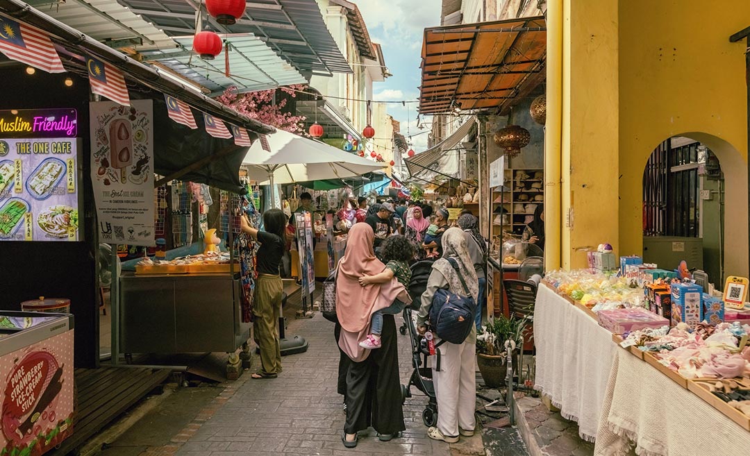 Locals and tourists walking along Concubine Lane past heritage shophouses and colourful decorations in Ipoh Old Town.